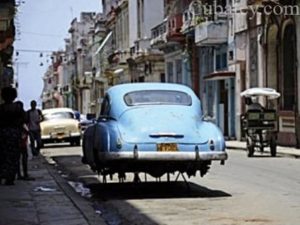 Un antiguo Chevrolet  por una calle de viejos edificios en La Habana.
